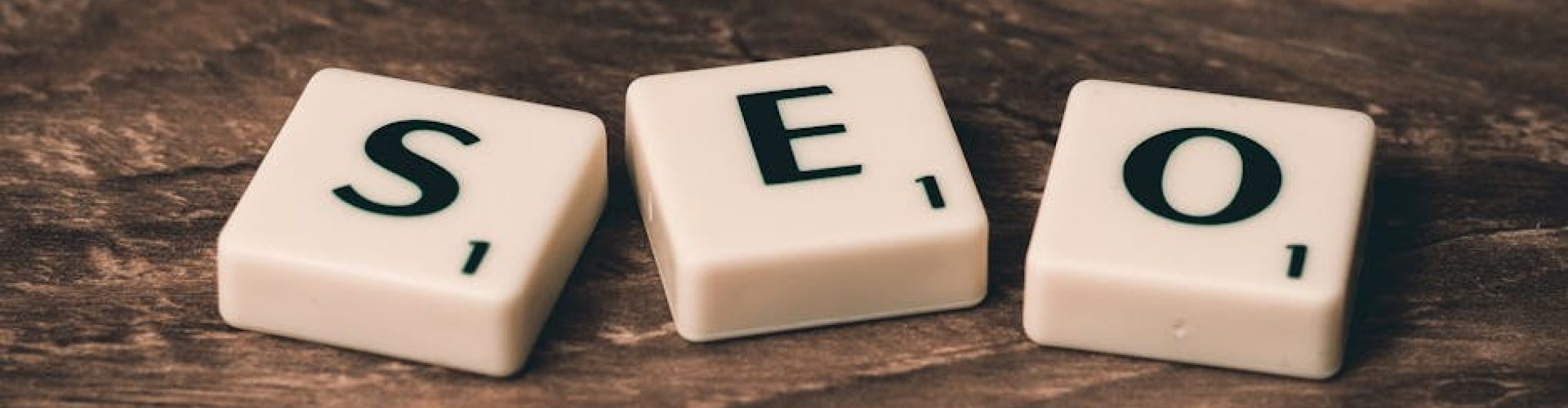 Scrabble tiles spelling 'SEO' on a wooden surface. Ideal for digital marketing themes.